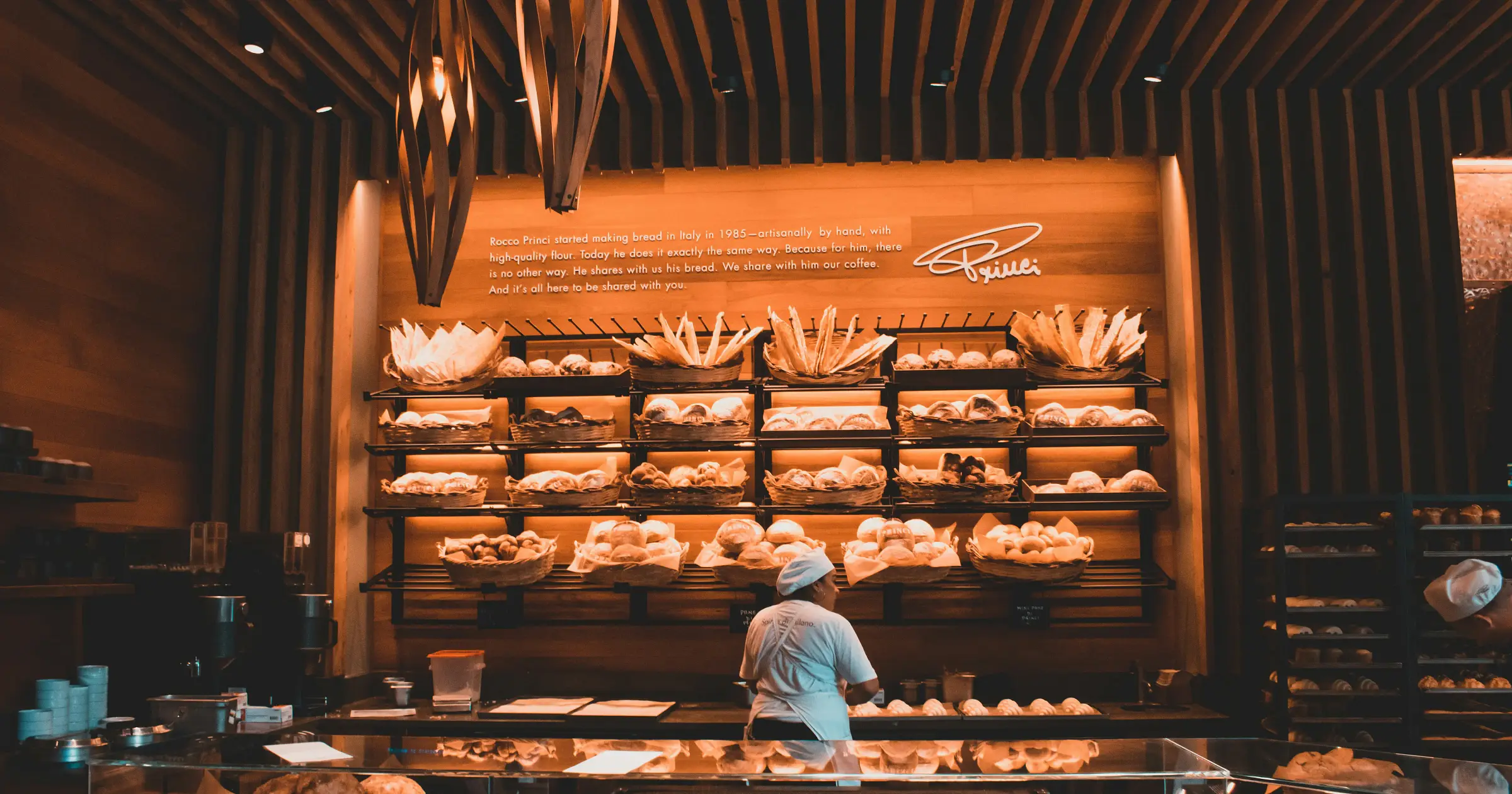 Baker working in a modern bakery with shelves of bread